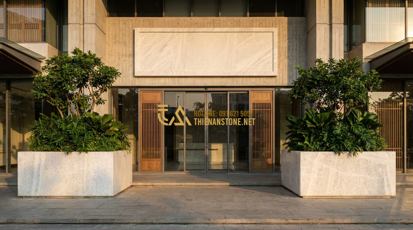 Tạo ảnh tiếng Anh: A luxury office entrance featuring a large natural stone signboard and two symmetrical massive stone planters with lush greenery. The composition follows Feng Shui principles, evoking a sense of stability, wealth, and professional success. Modern corporate architecture, sunset lighting.