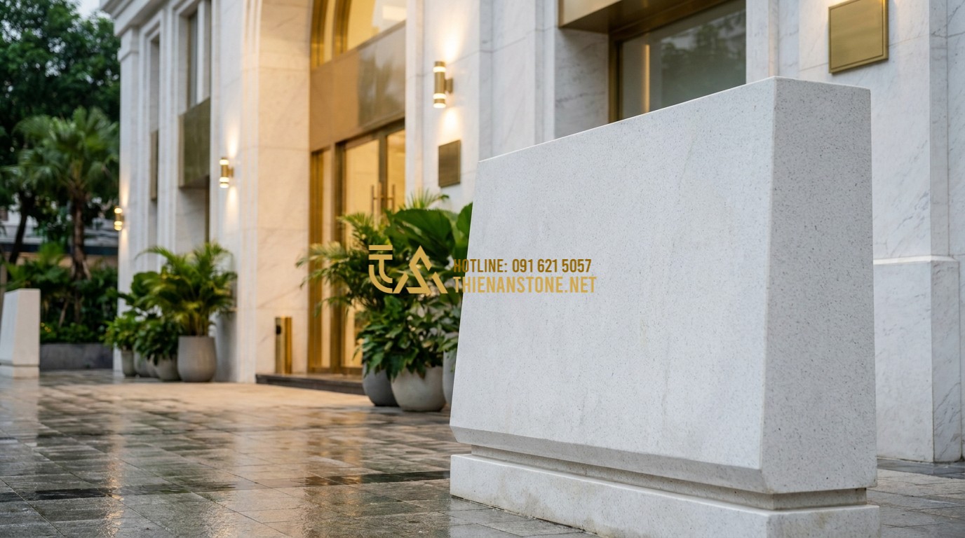 Tạo ảnh tiếng Anh: A luxury modern office building entrance featuring high-end dark stone wall cladding and a large natural stone monument signboard with professional golden engraving. Sophisticated and prestigious atmosphere.