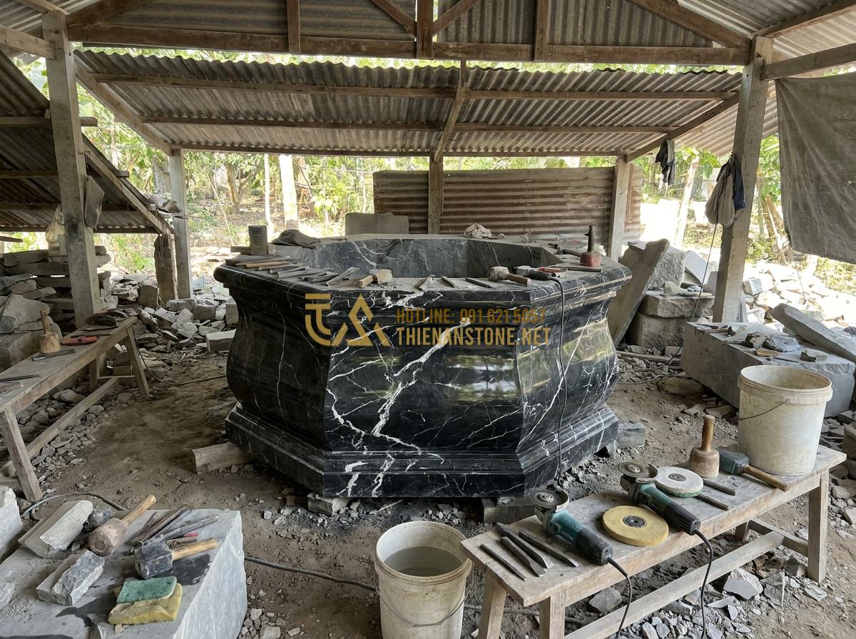 Tạo ảnh tiếng Anh: Detailed behind-the-scenes professional image of skilled Vietnamese stone artisans at a traditional workshop carefully carving and polishing a large natural stone garden well, tools and stone blocks visible, focused and artistic atmosphere with natural daylight, realistic documentary style photography