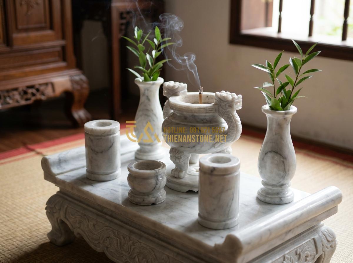 Create a professional high-resolution image of various stone worship items including incense burners, candle holders and flower vases carved from natural marble stone, displayed elegantly on a stone altar in a traditional Vietnamese home with gentle incense smoke and soft natural light, realistic and detailed craftsmanship style