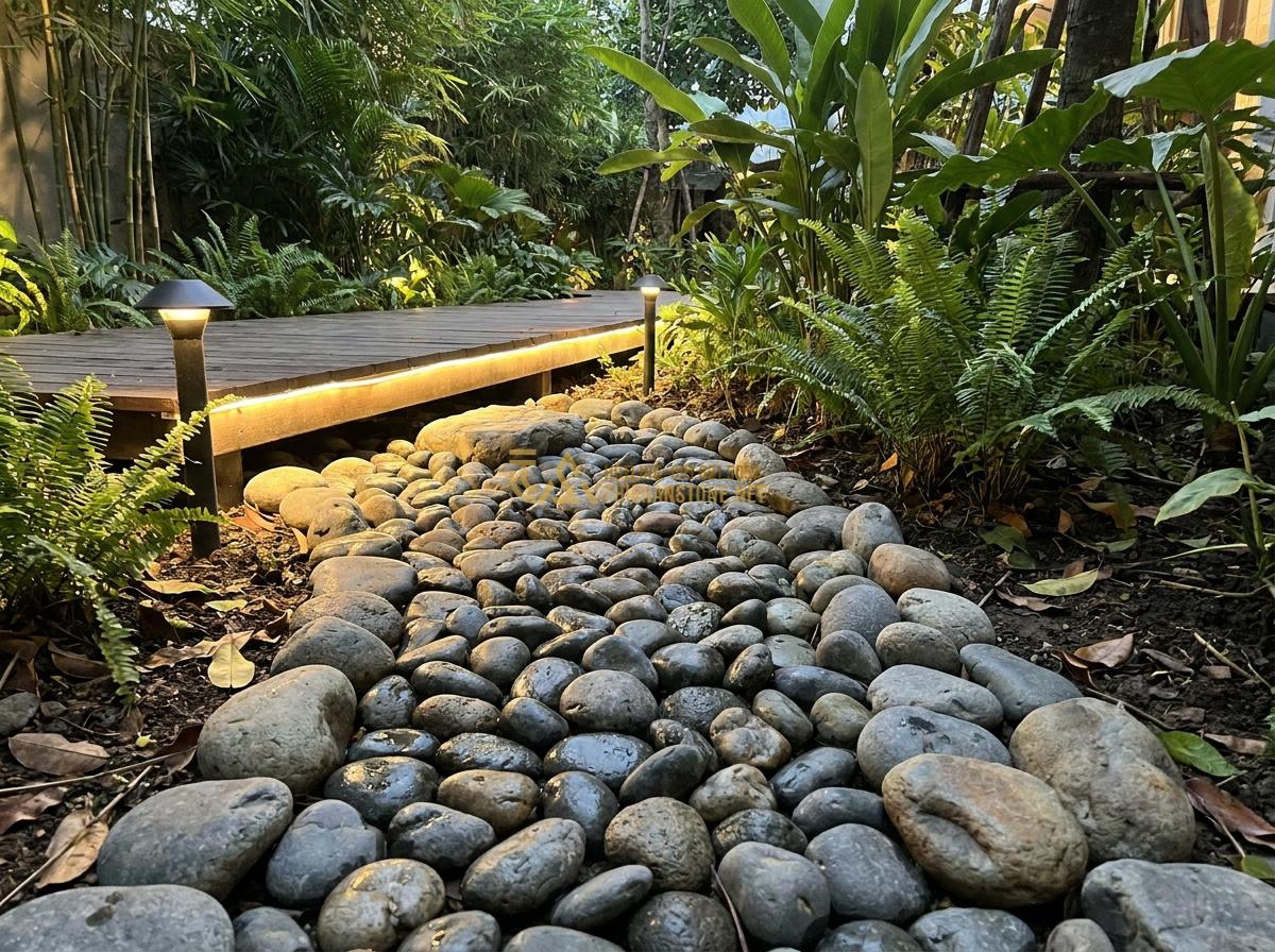 Báo Giá Đá Cuội Đen, Trắng, Vân Mây Trang Trí Tự Nhiên Rẻ Nhất - Black river pebbles used as pathway border in tropical garden design with modern