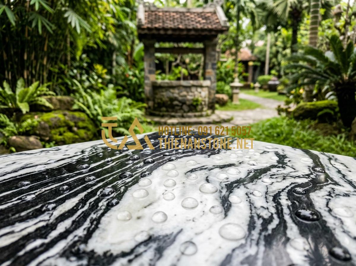 Bí quyết vệ sinh giếng đá tự nhiên sạch bong rêu mốc chỉ trong 15 phút - Tạo ảnh tiếng Anh: Water droplets beading up on a polished stone surface, showin