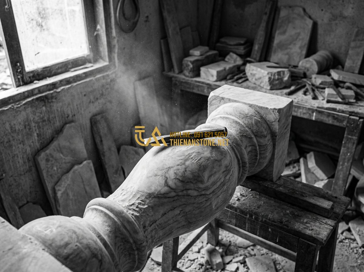 Cách Chọn Con Tiện Đá Tự Nhiên Đẹp & Bền Mãi Cho Lan Can Cầu Thang - Tạo ảnh tiếng Anh: [A focused stone carver working with a chisel on a stone balu