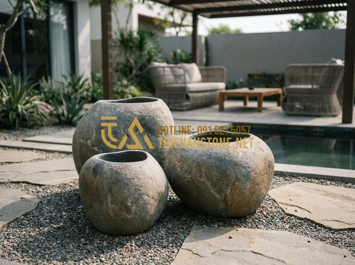Lu đá tiểu cảnh: Tại sao vại đựng nước bằng đá tự nhiên lại được đại gia săn đón? - Hình 4 Lu đá tiểu cảnh: Tại sao vại đựng nước bằng đá tự nhiên lại được đại gia săn đón? - Tạo ảnh tiếng Anh: A group of three stone jars of varying heights arranged artis