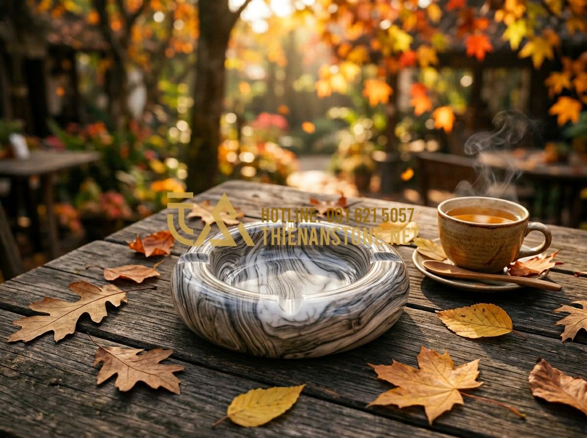 So sánh gạt tàn đá Cẩm thạch, Serpentine và Canxit: Nên chọn loại nào? - Tạo ảnh tiếng Anh: A wooden-grain stone ashtray placed on a rustic wooden outdoo
