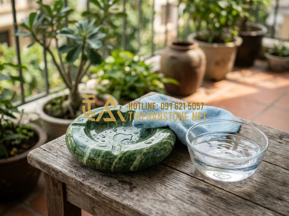 Tại sao gạt tàn đá tự nhiên lại bền và được ưa chuộng hơn gạt tàn sứ? - Tạo ảnh tiếng Anh: A person gently cleaning a smooth marble ashtray with a soft