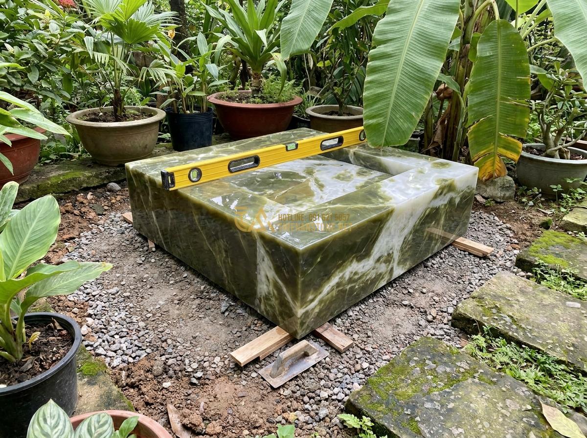 Thiết Kế & Thi Công Đài Phun Nước Bằng Đá Sân Vườn Chuẩn Phong Thủy | Quy Trình Chuyên Nghiệp - Hình 6 Thiết Kế & Thi Công Đài Phun Nước Bằng Đá Sân Vườn Chuẩn Phong Thủy | Quy Trình Chuyên Nghiệp - Installation process image showing a mini stone fountain being placed in a small